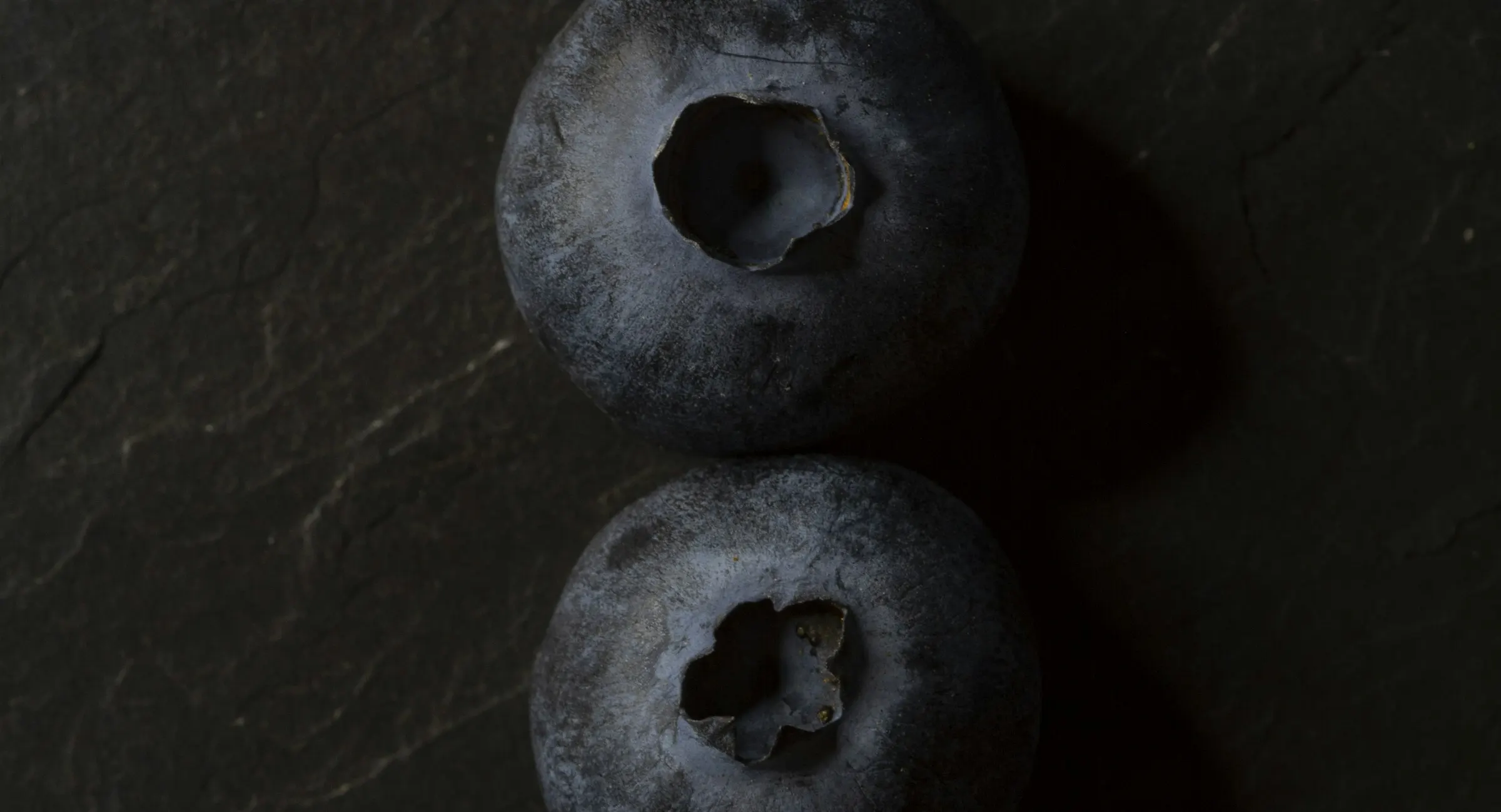 Three blueberries on dark stone